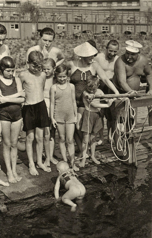 Jeden a půl roku starý Pepíček Mejzlík vylézá z vody po plaveckém tréninku pod dohledem svého otce. (Pestrý týden, 1940)